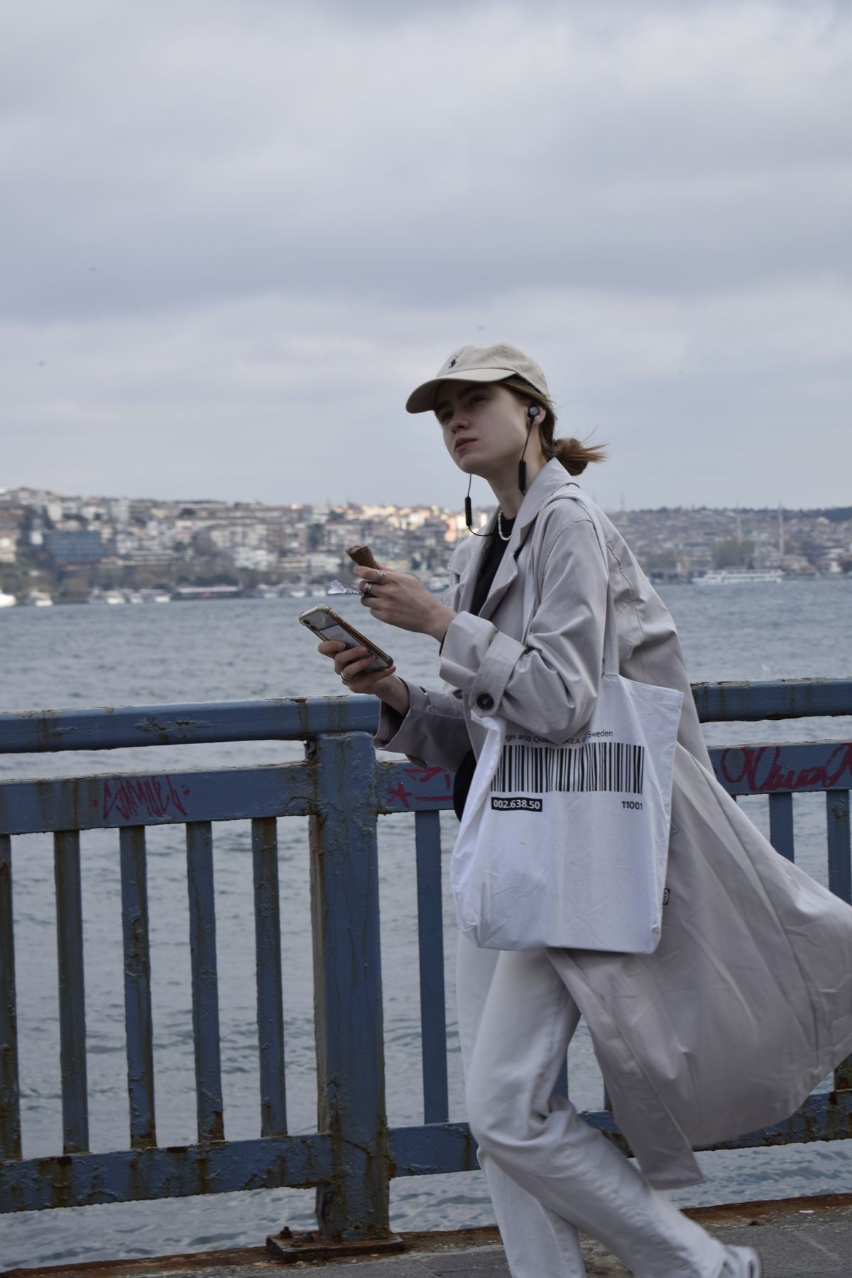 A woman walking outside with headphones and a smartphone