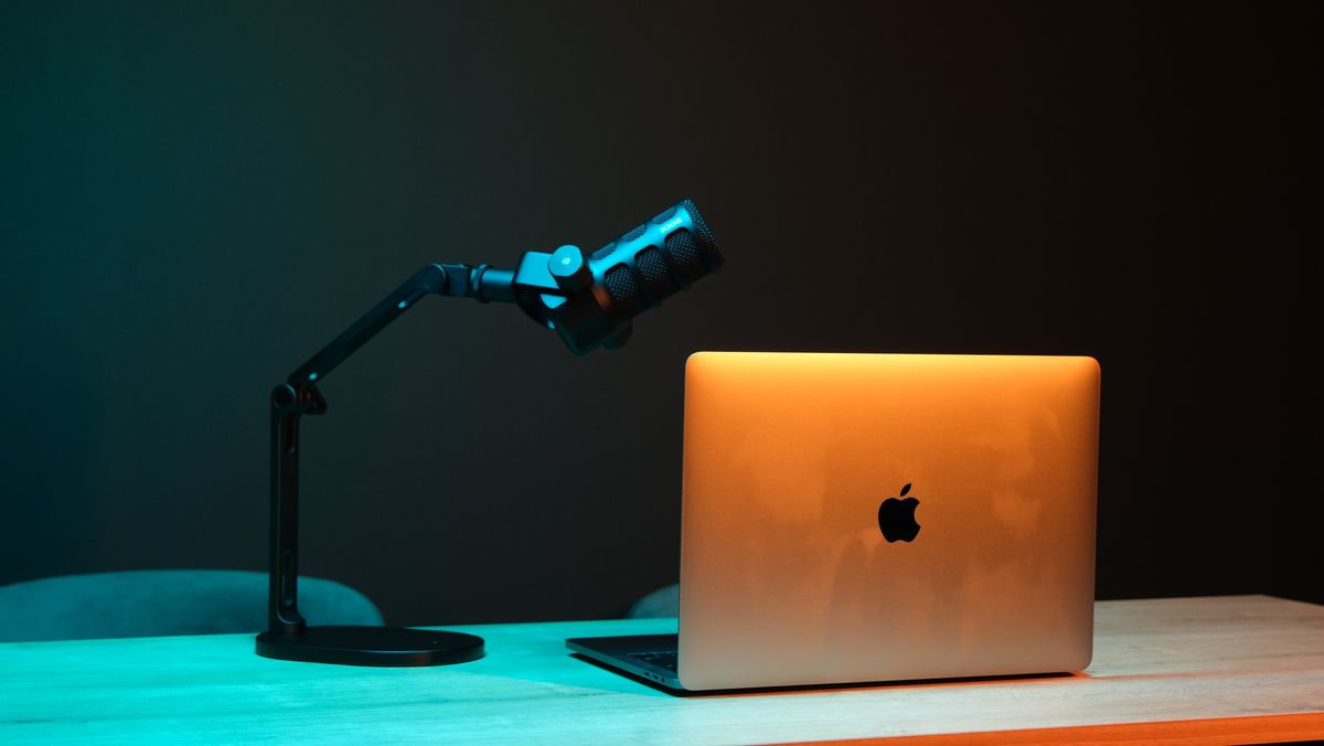 A laptop and microphone on a wooden home studio desk