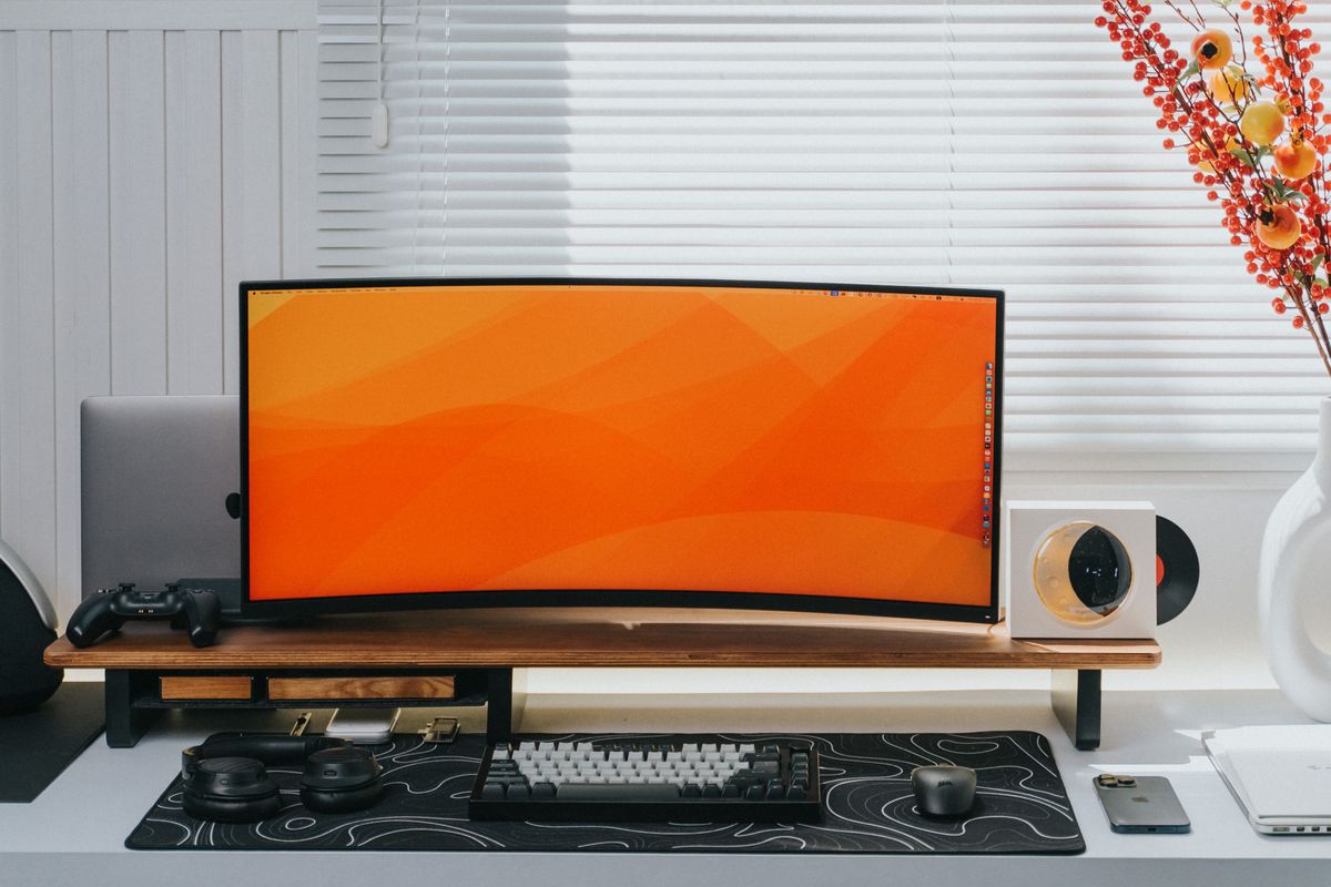 A curved monitor and keyboard on an organized home desk