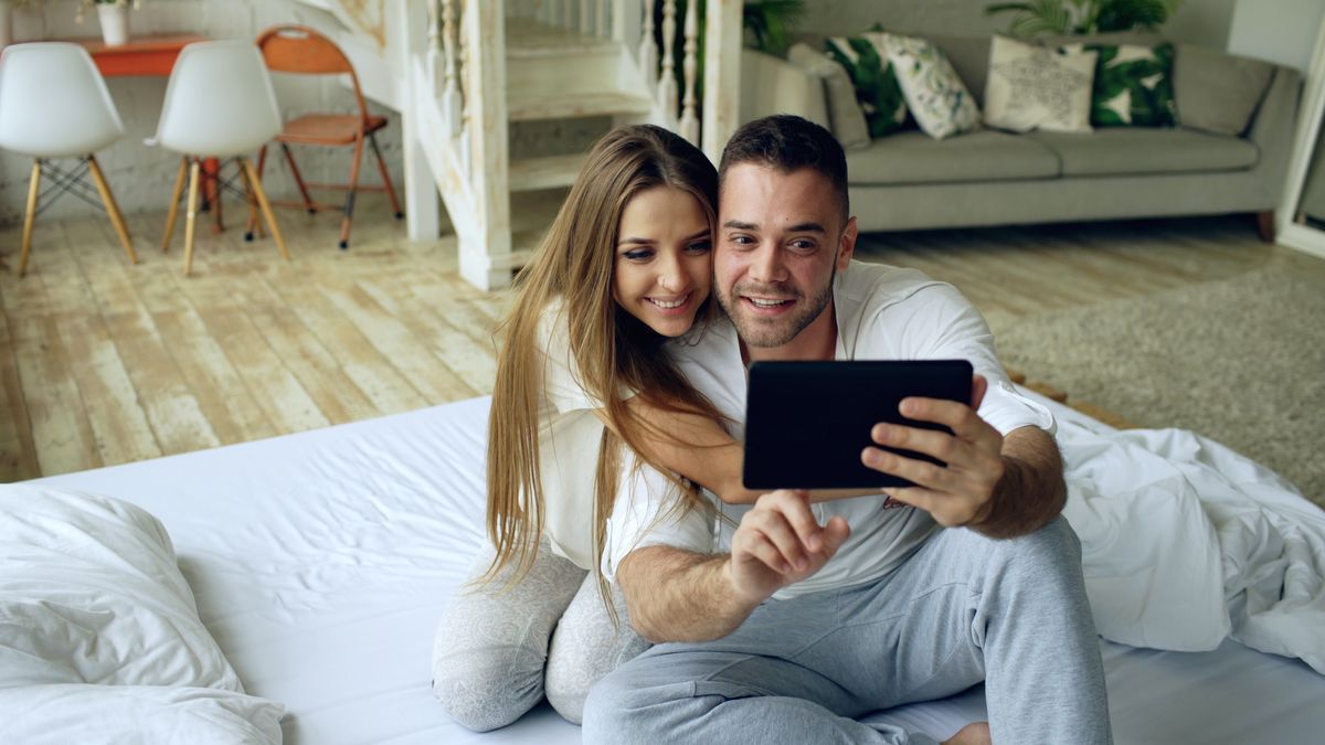 A couple relaxing at home while using a tablet