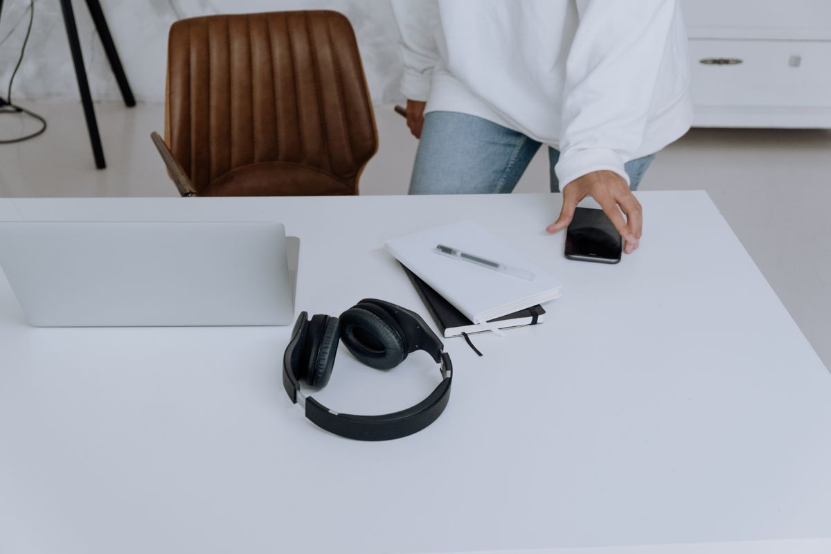 Headphones, a laptop and a smartphone arranged on a home work desk