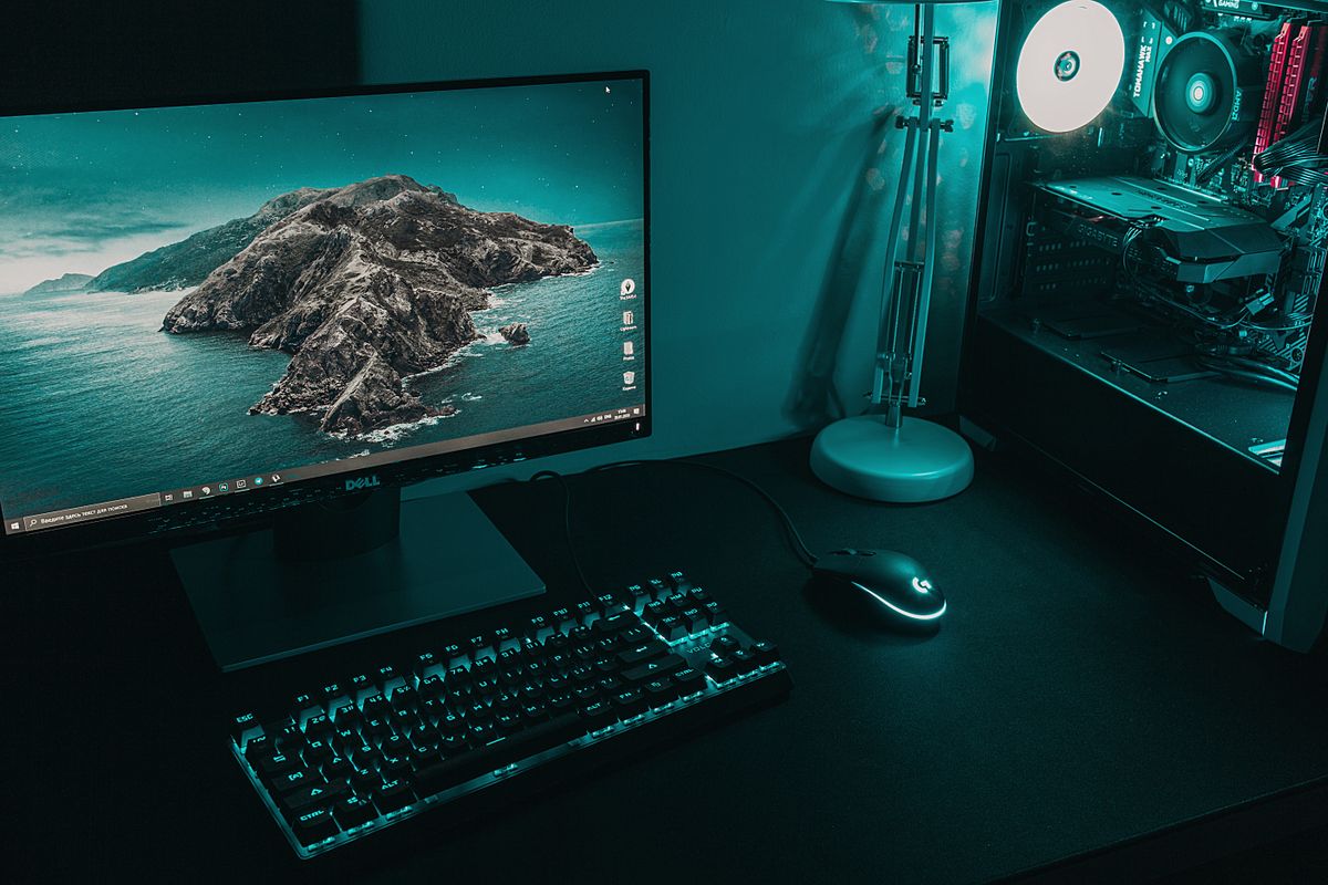 A desktop computer, keyboard and mouse in an illuminated workspace