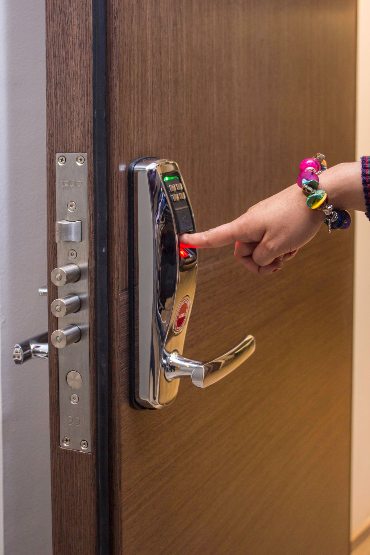 A hand using the fingerprint reader on a digital door lock